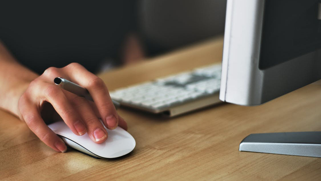 Person clicking a mouse in front of a computer