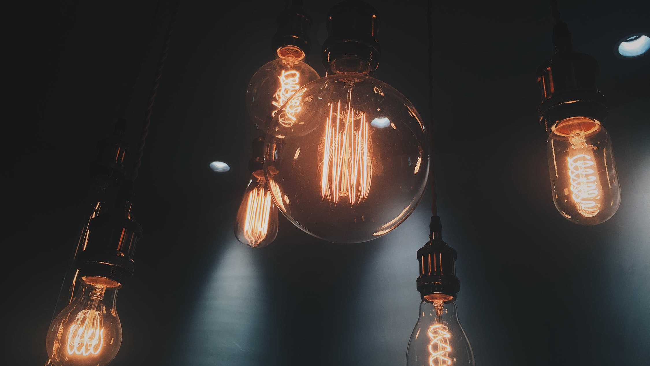 Multiple illuminated light bulbs hanging from a ceiling