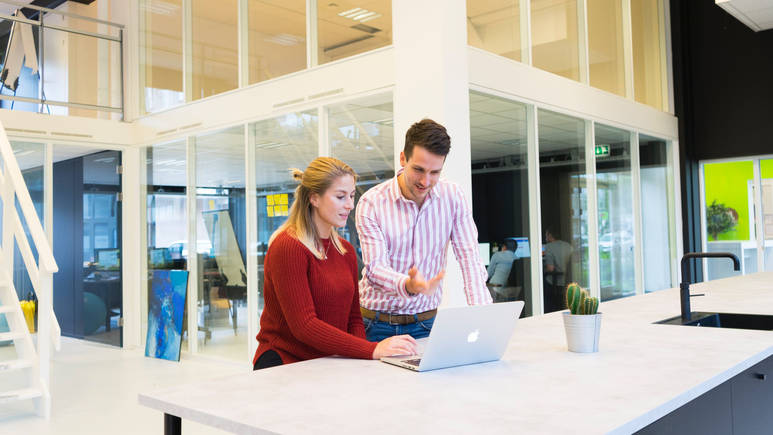 two people in an office building working on a laptop