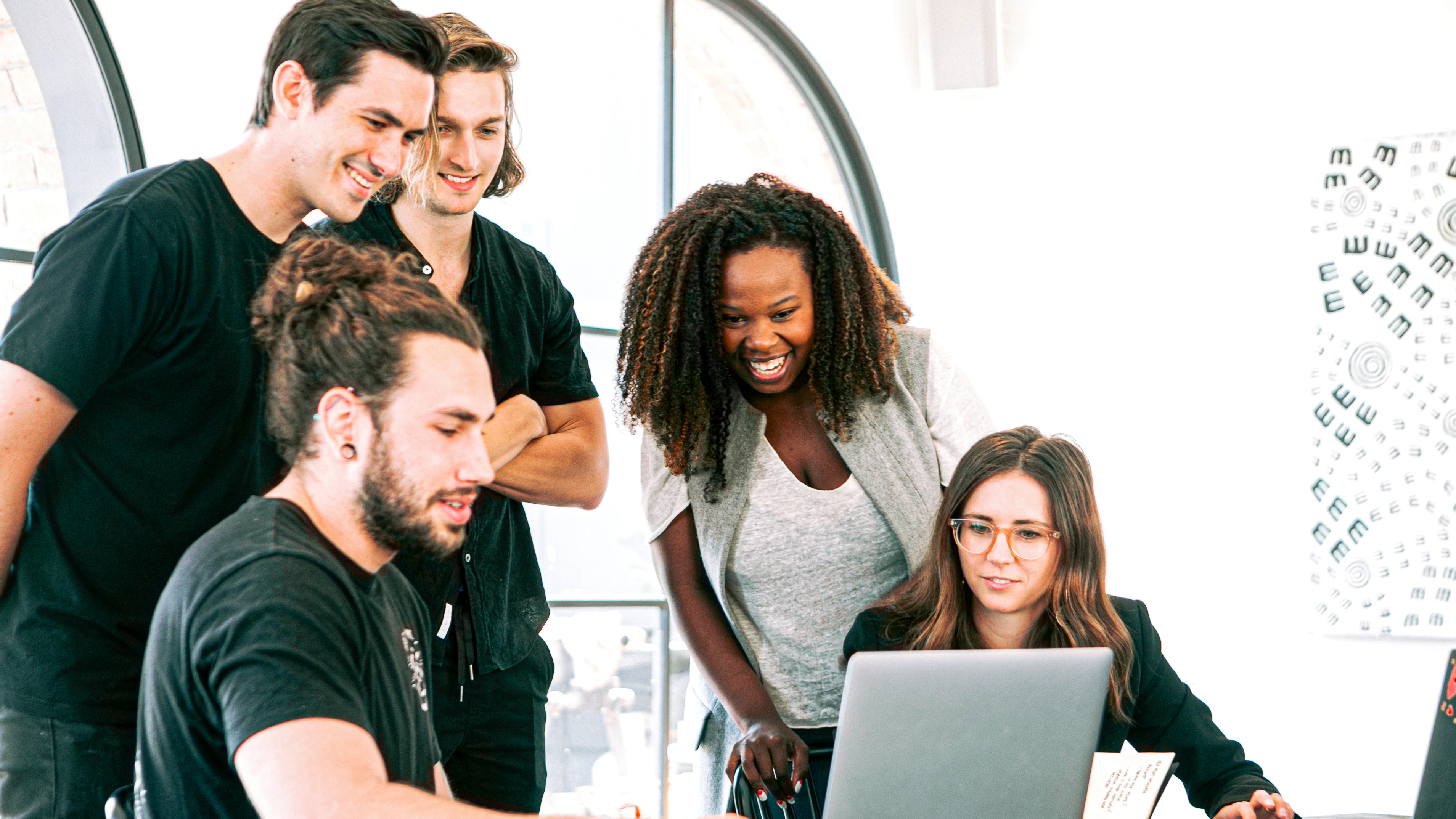 five people around a computer at a desk