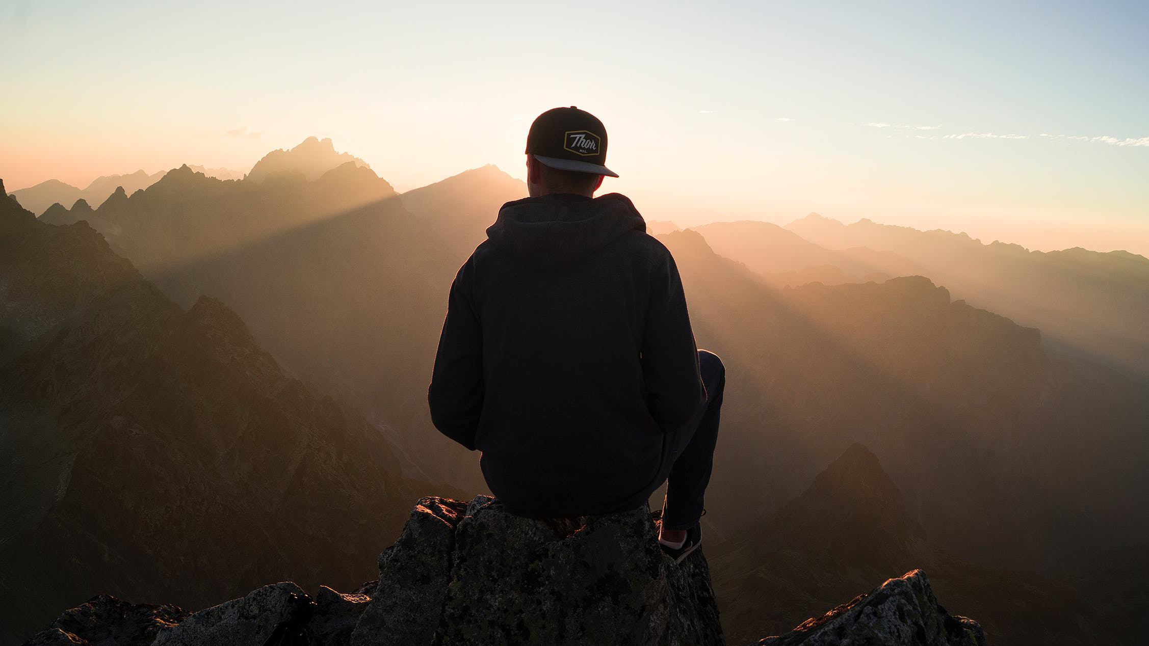 peron sitting on top of a hill watching the sunrise