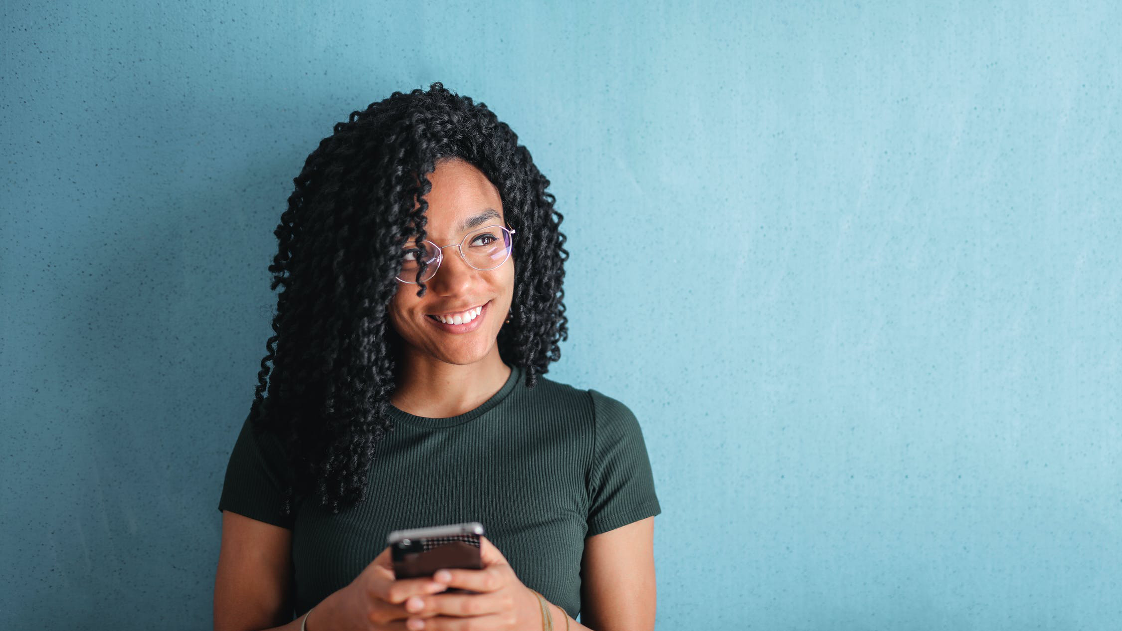 Woman with a phone smiling at something off-camera