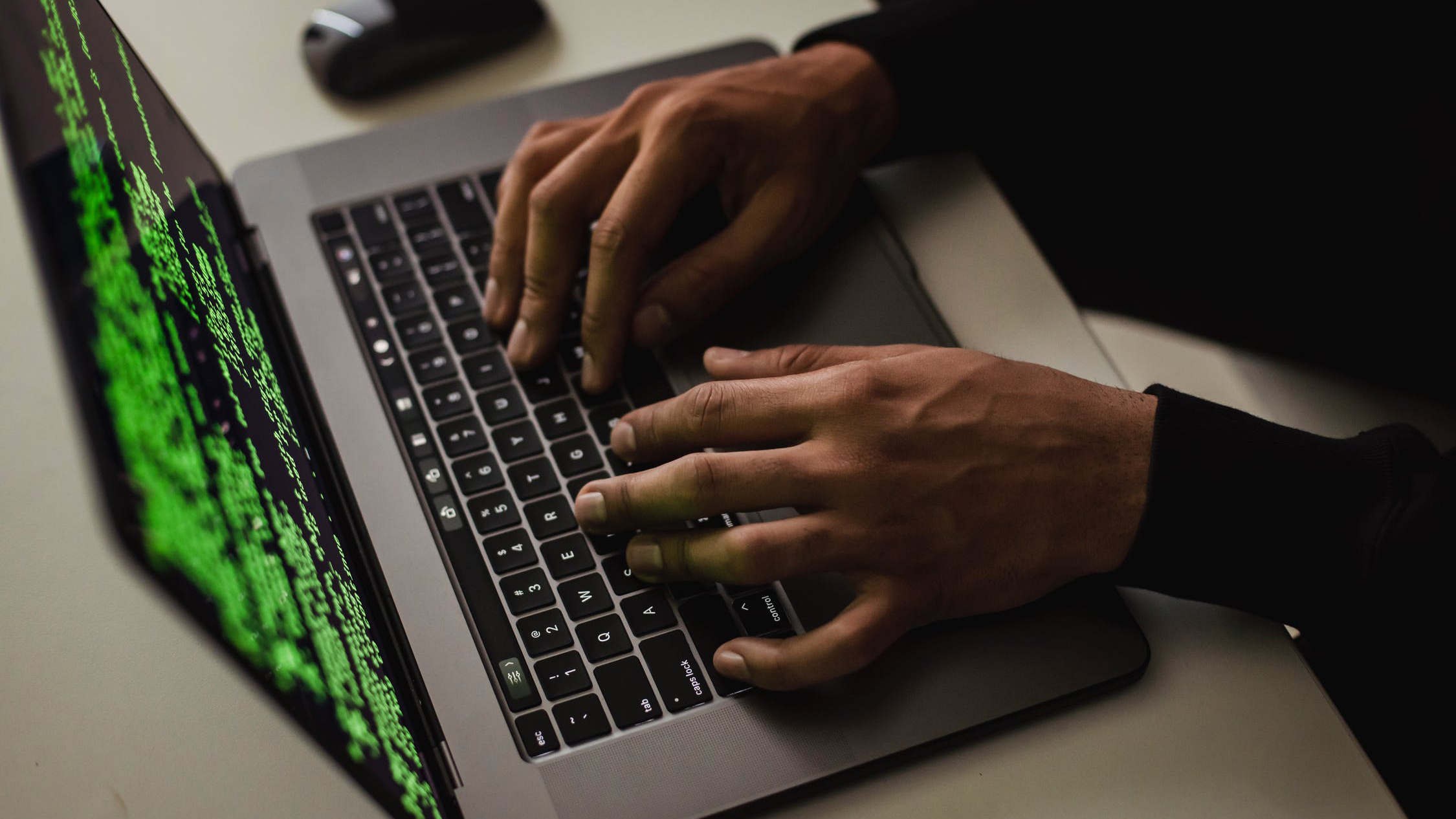 person typing on a computer with green code