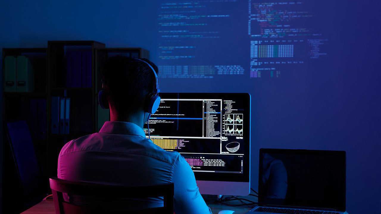 Person typing on a computer with headphones on