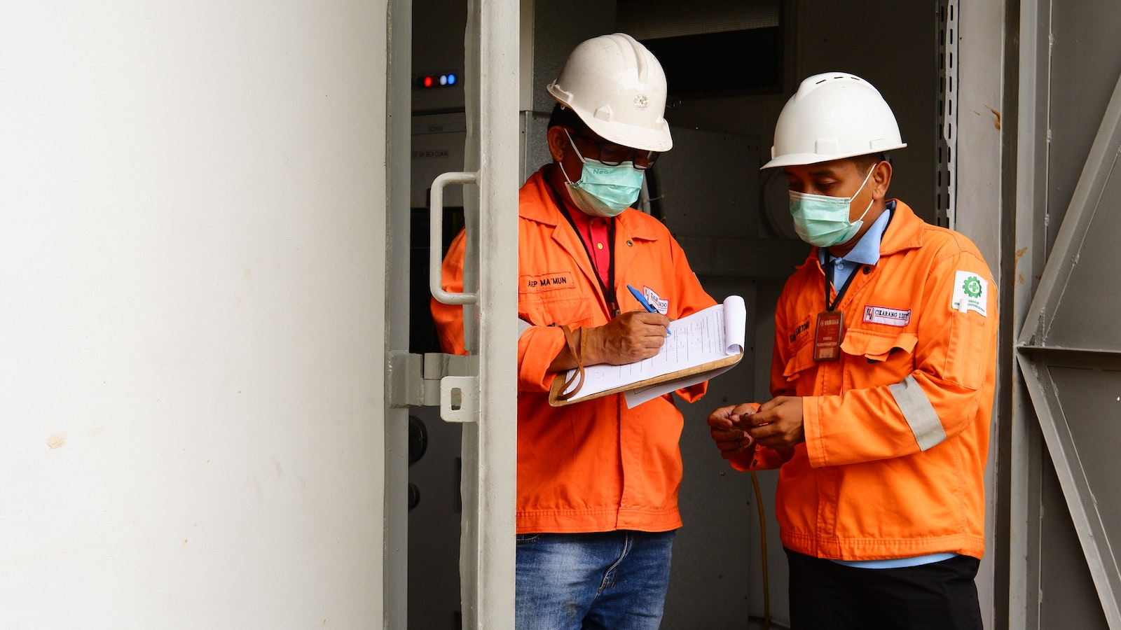 Men in orange jackets and hardhats standing in a doorway