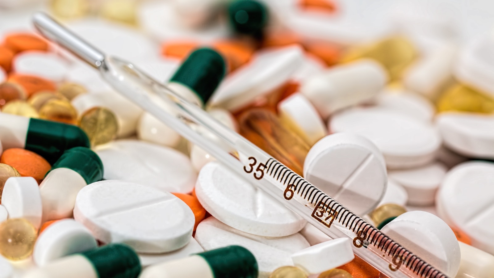 Pipette in front of a pile of various pills