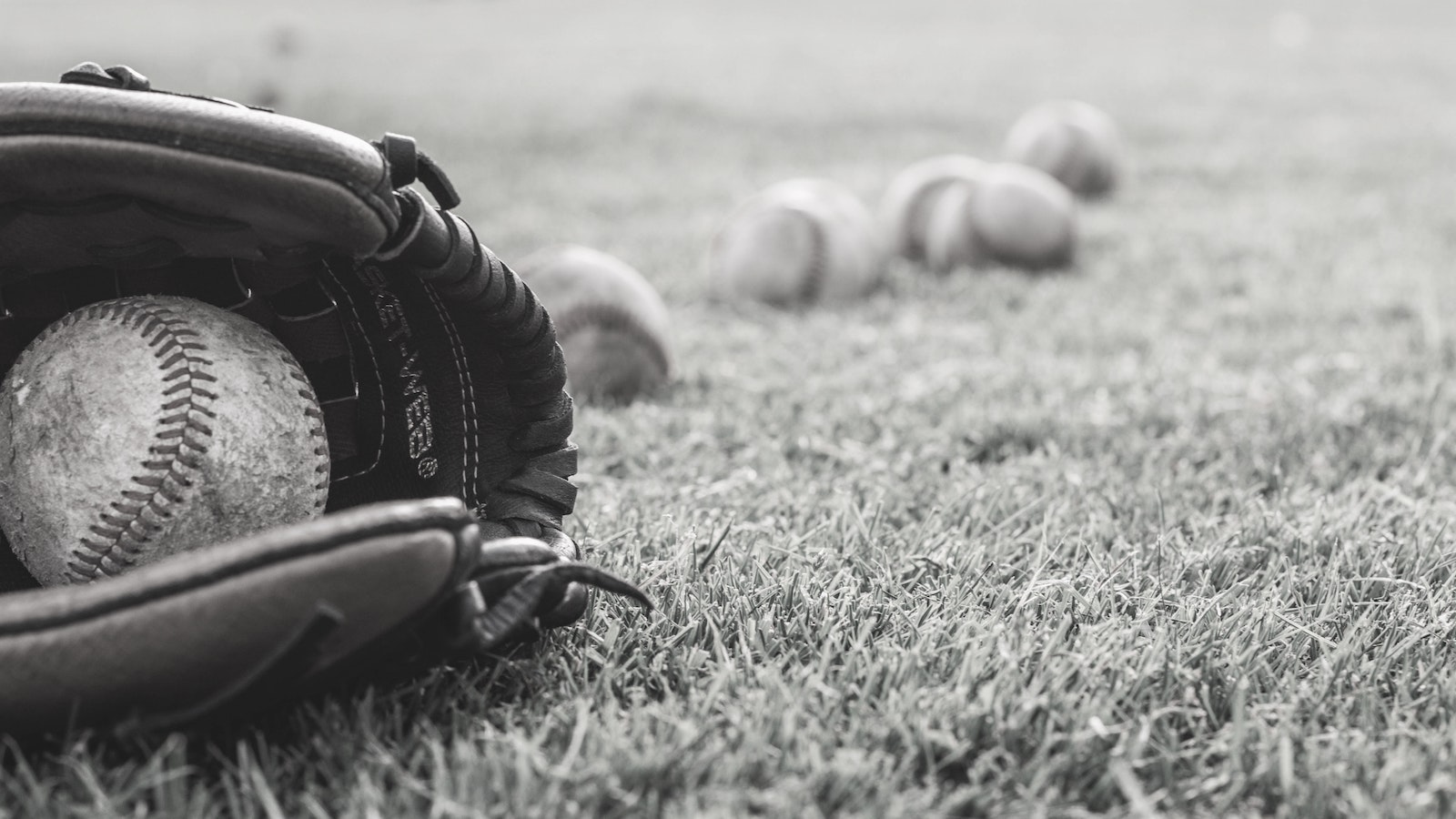 Baseball in glove with other baseballs behind it