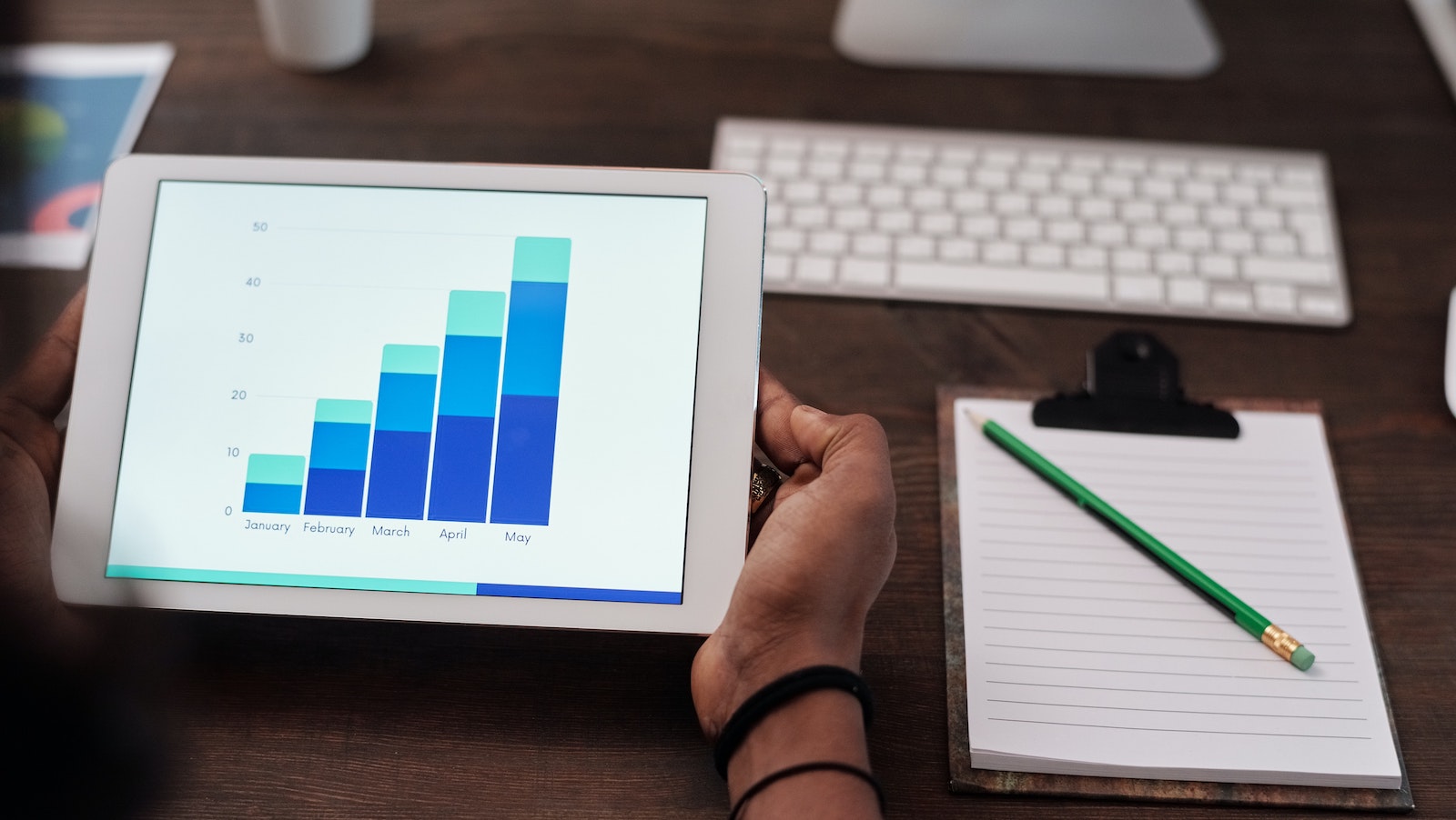 Person hold a tablet with a chart shown next to pencil and paper