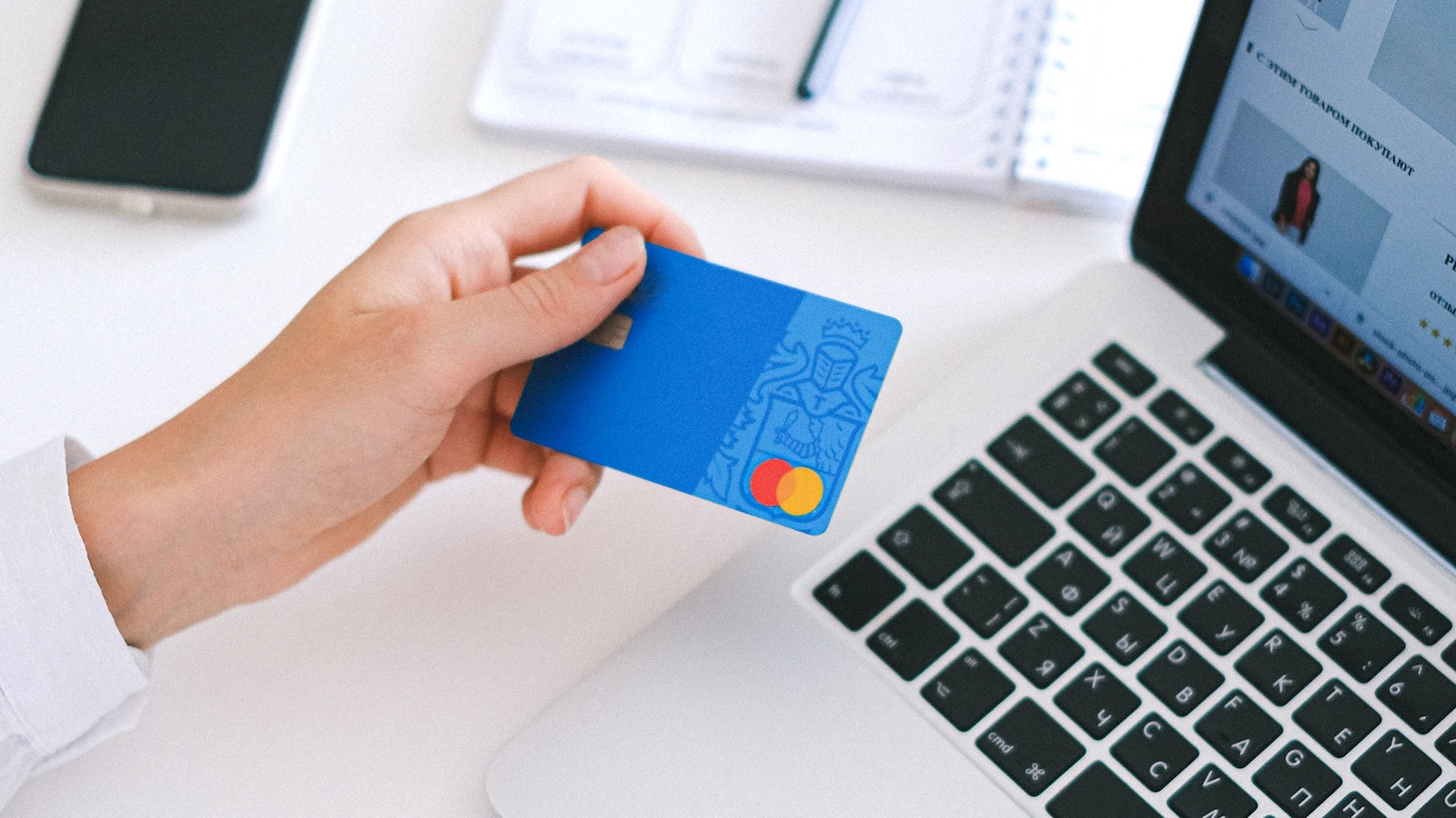 Person holding credit card in front of a laptop