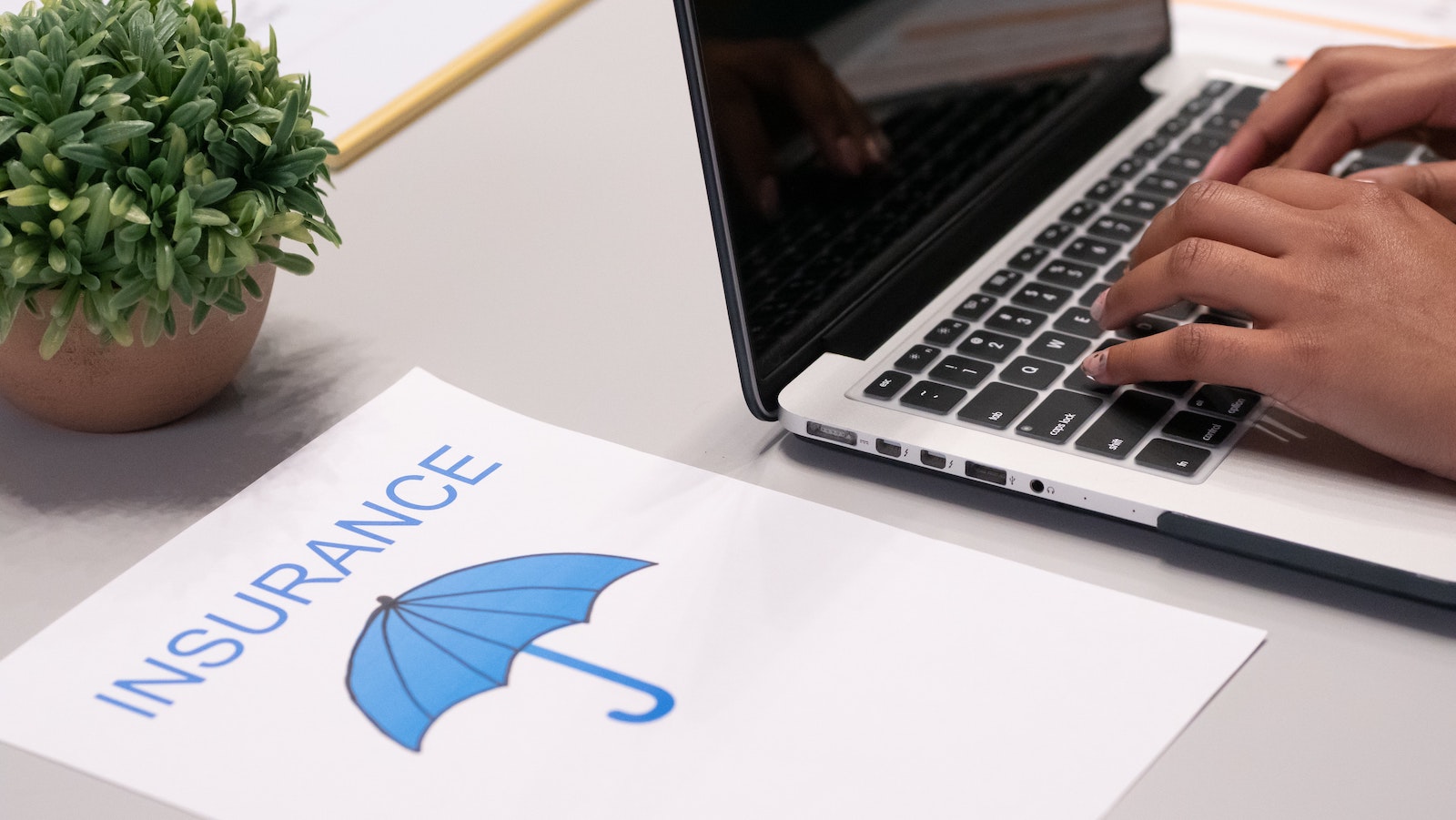 Paper with an umbrella and "INSURANCE" written on it next to a laptop