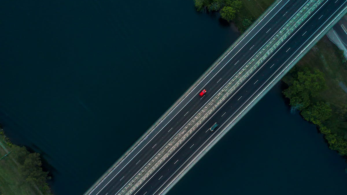 A bridge with one car on it across a body of water