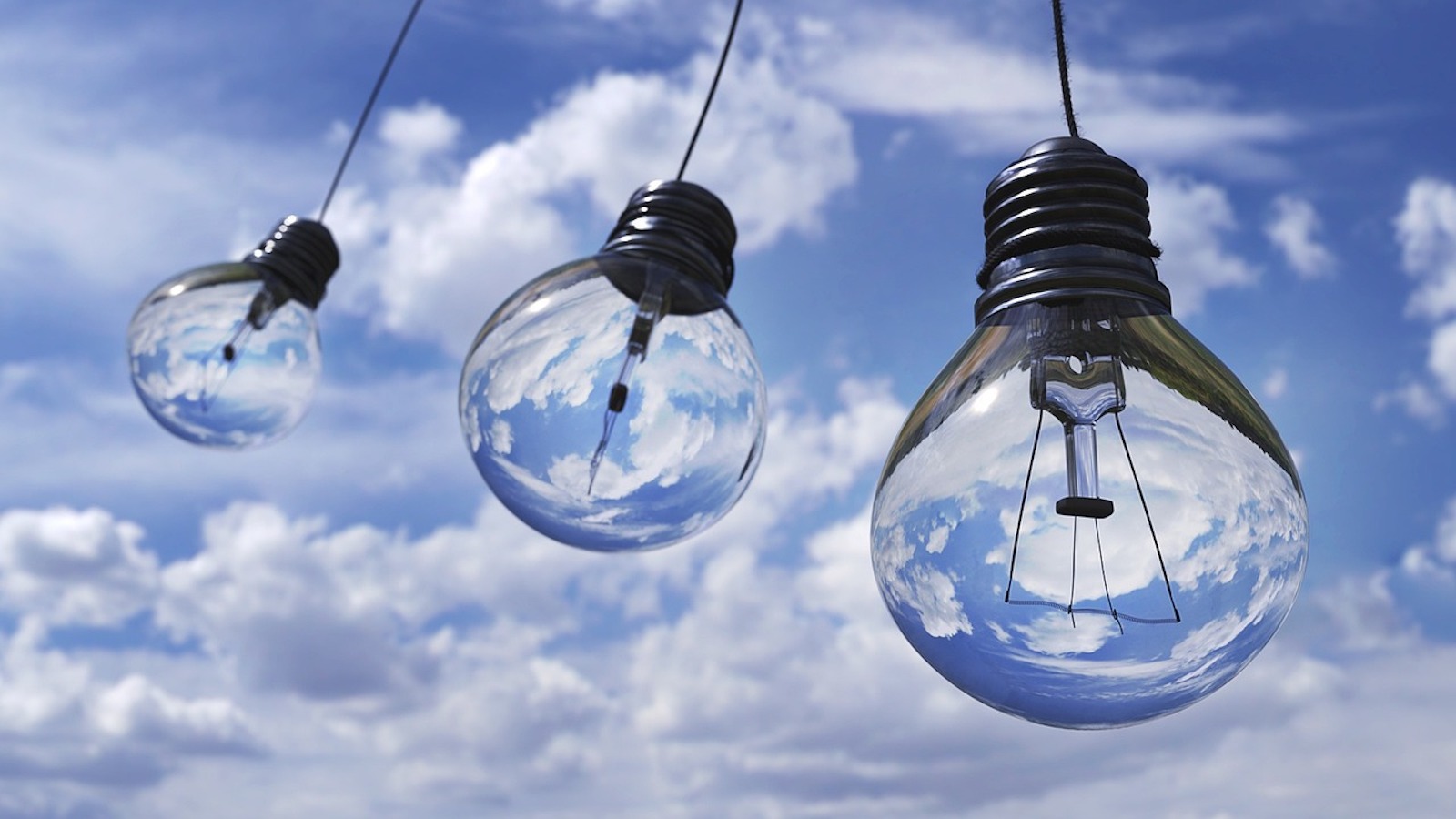 Three lightbulbs in front of a cloudy blue sky