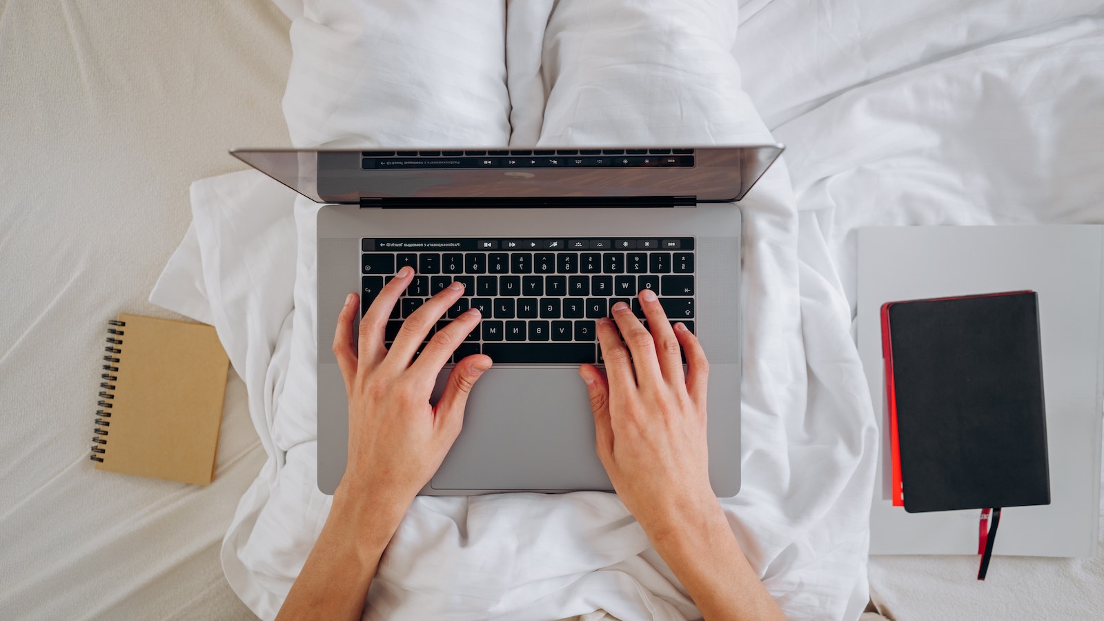 Person in bed typing on a laptop