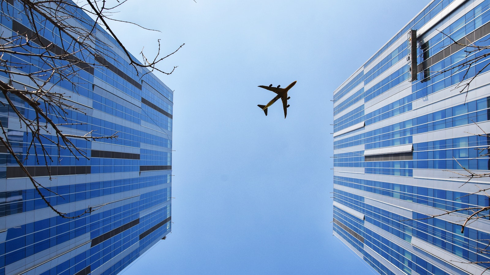 A plane flying above two tall buildings