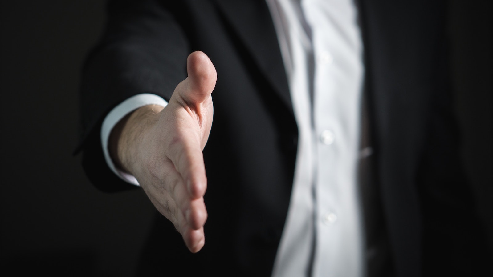 Person in suit sticking out their hand for a handshake