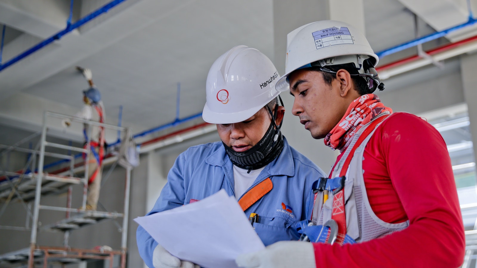 Two people in hard hats looking at a sheet of paper