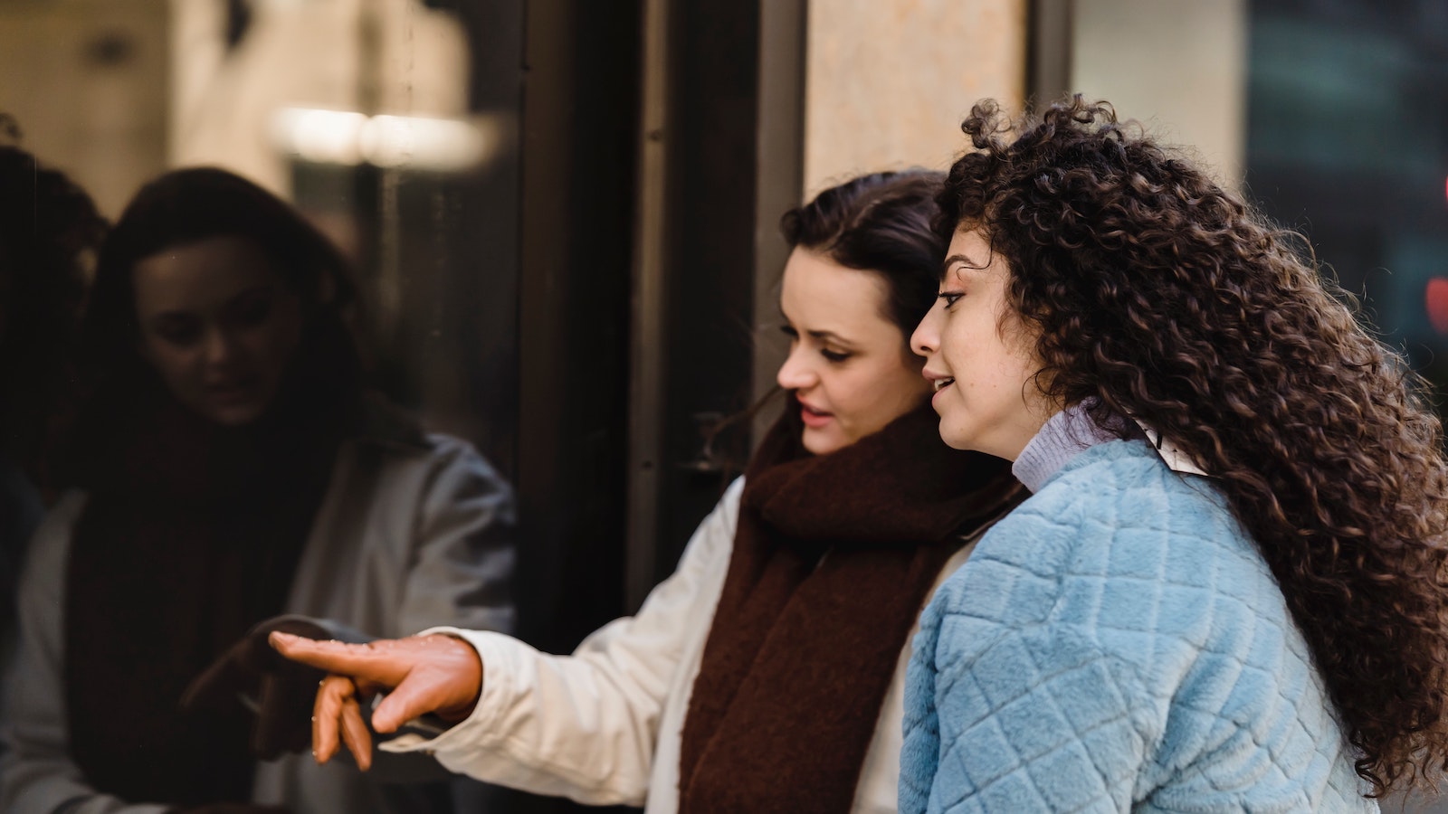 Two women looking through a window and pointing