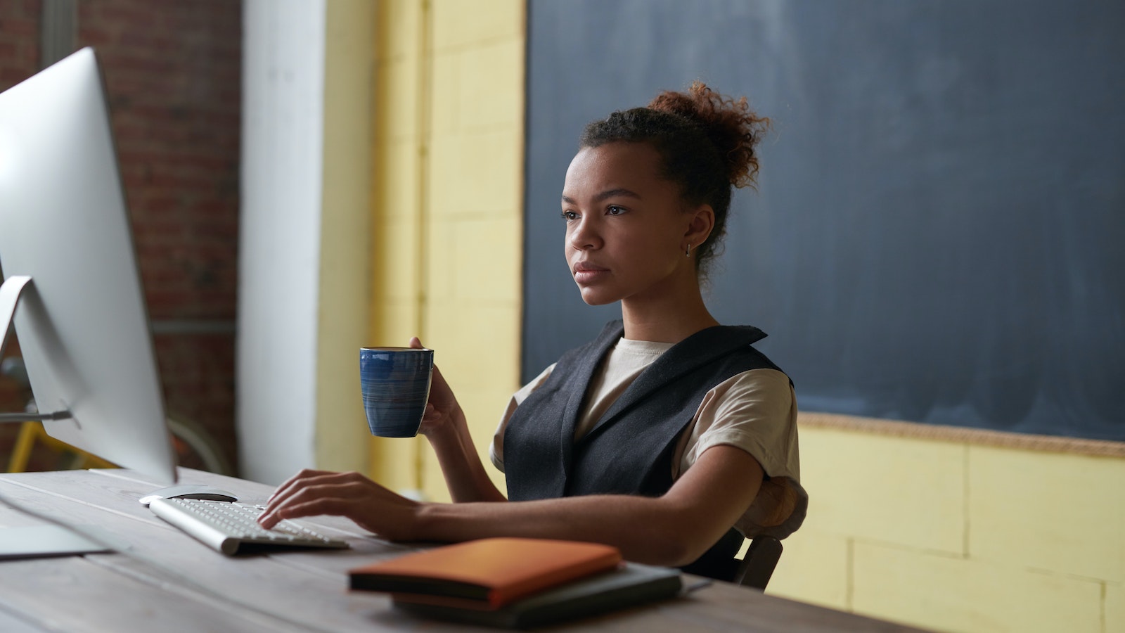 Woman holding a mug and typing on a computer