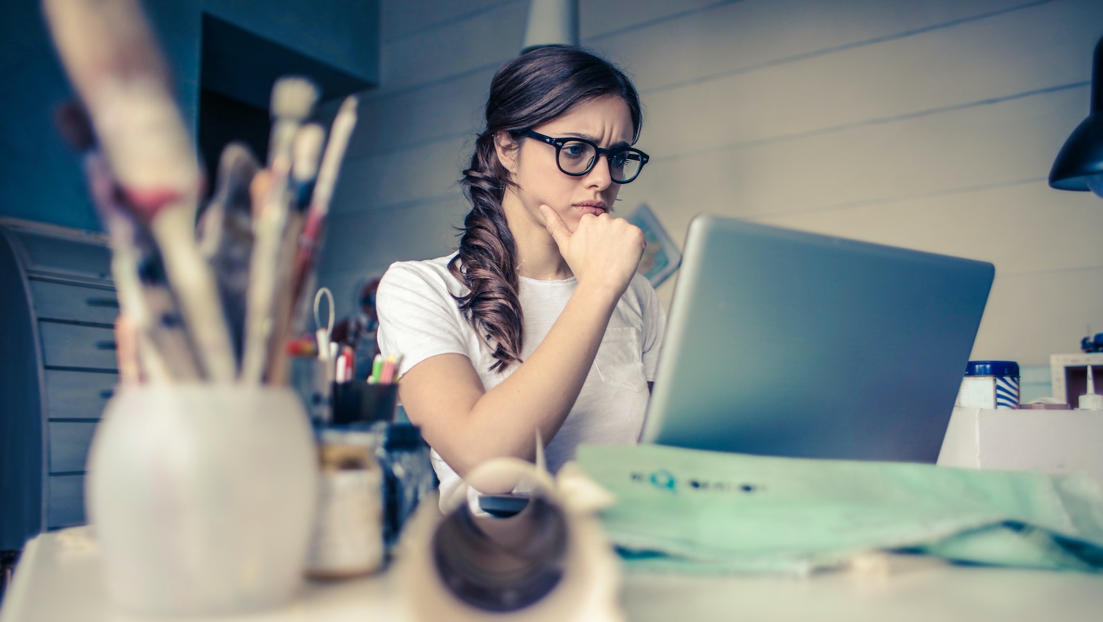 Woman at a desk in front of a computer thinking