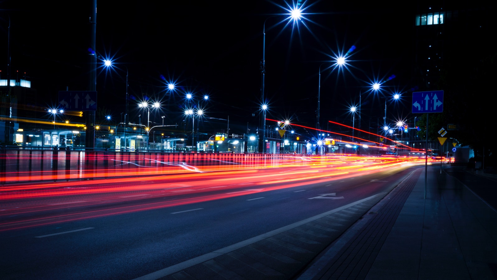 A road with streets lamps and blurred red lights 