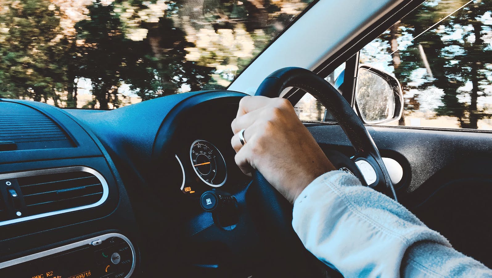 Person in a car with one hand on the steering wheel