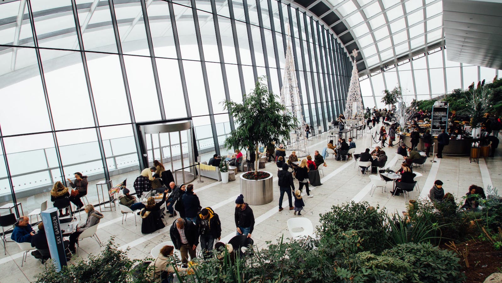 Open glass building with many people sitting at tables