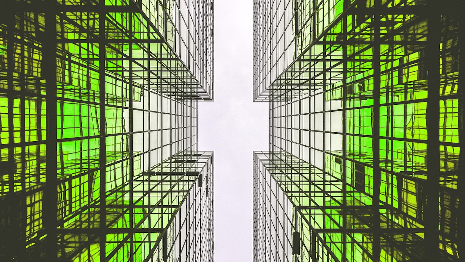 Low angle photo of two tall buildings with green lights