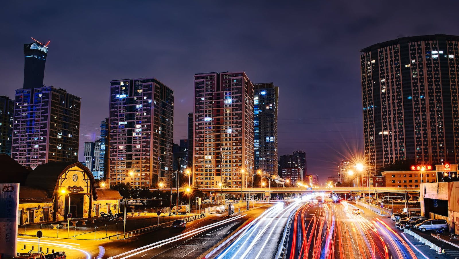 City at night lit up and with red and white blurred lines representing cars