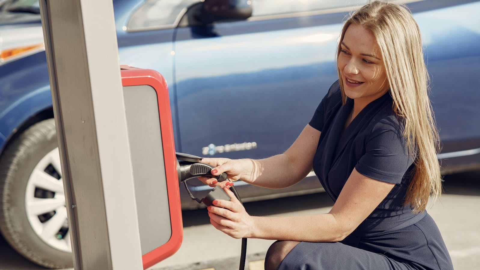 Woman at an plugging her car into an electronic vehicle charger