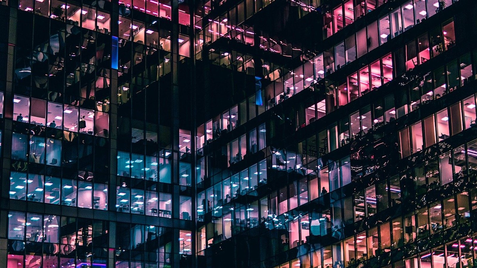Large office building at night with windows lit up