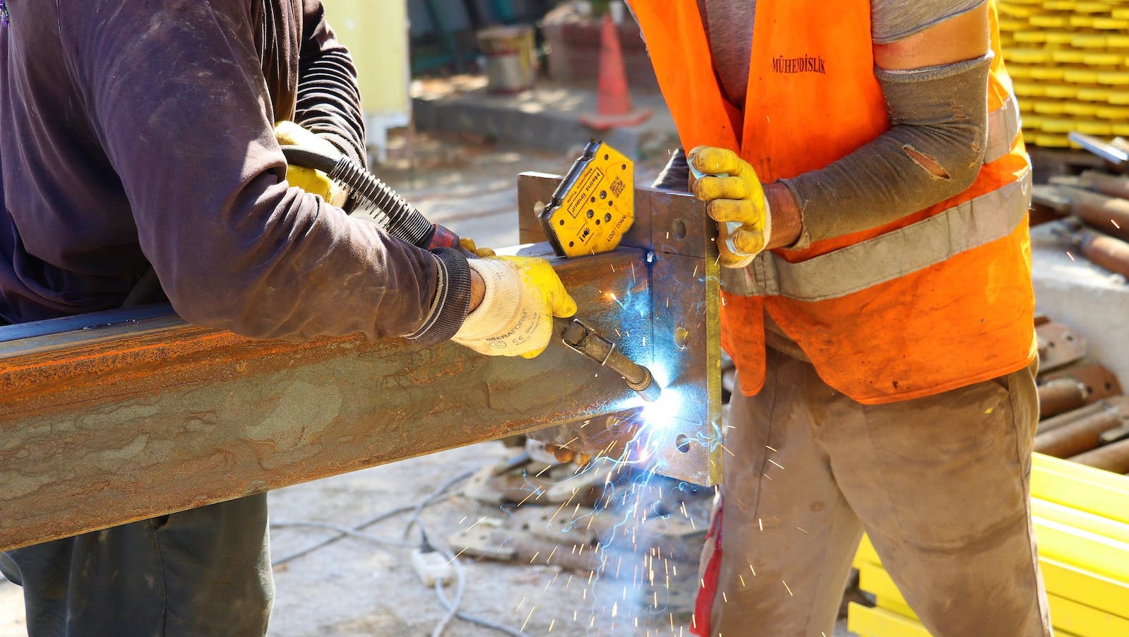Two workers using a welding machine on a construction site