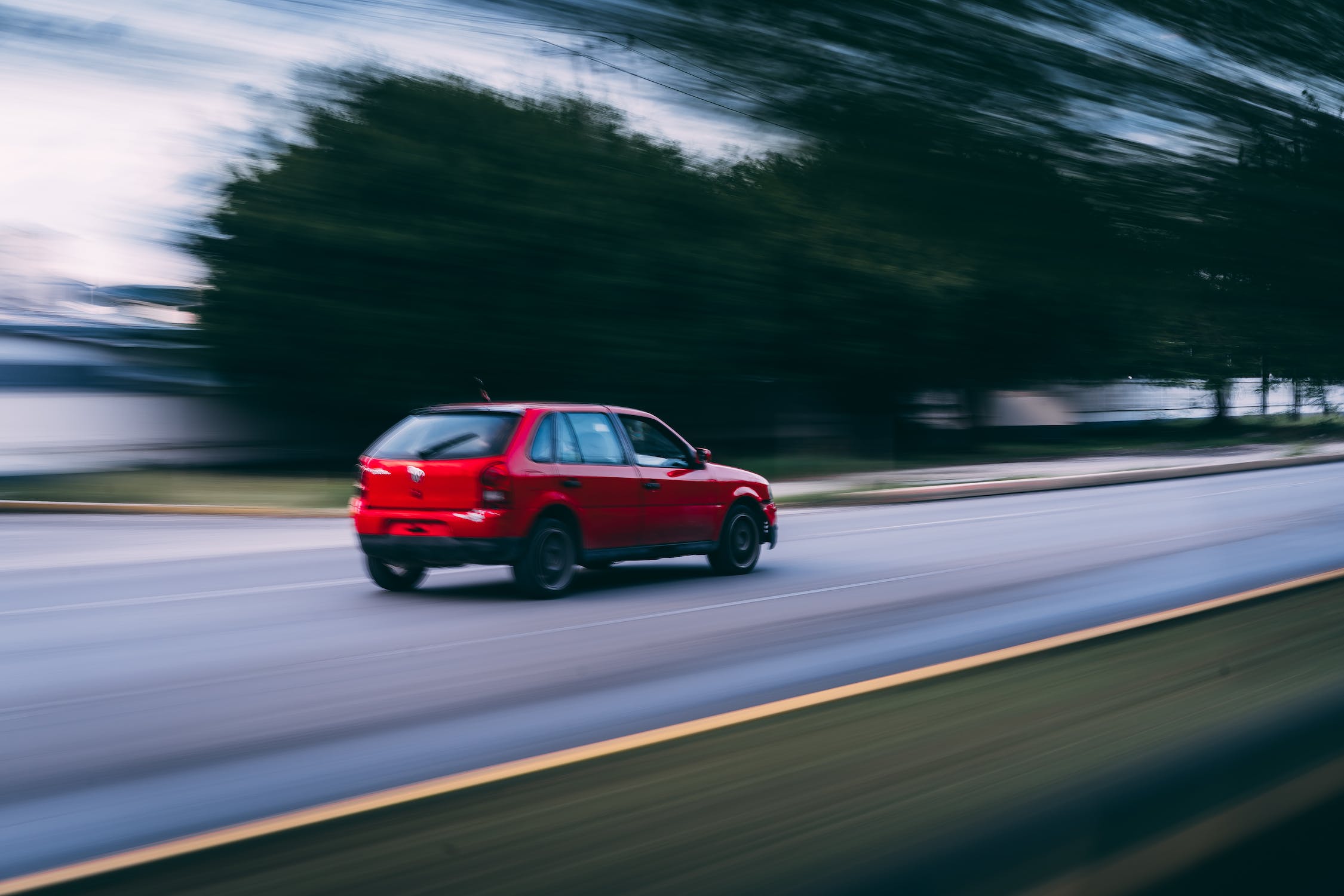 Red car on a road with a background of trees blurred