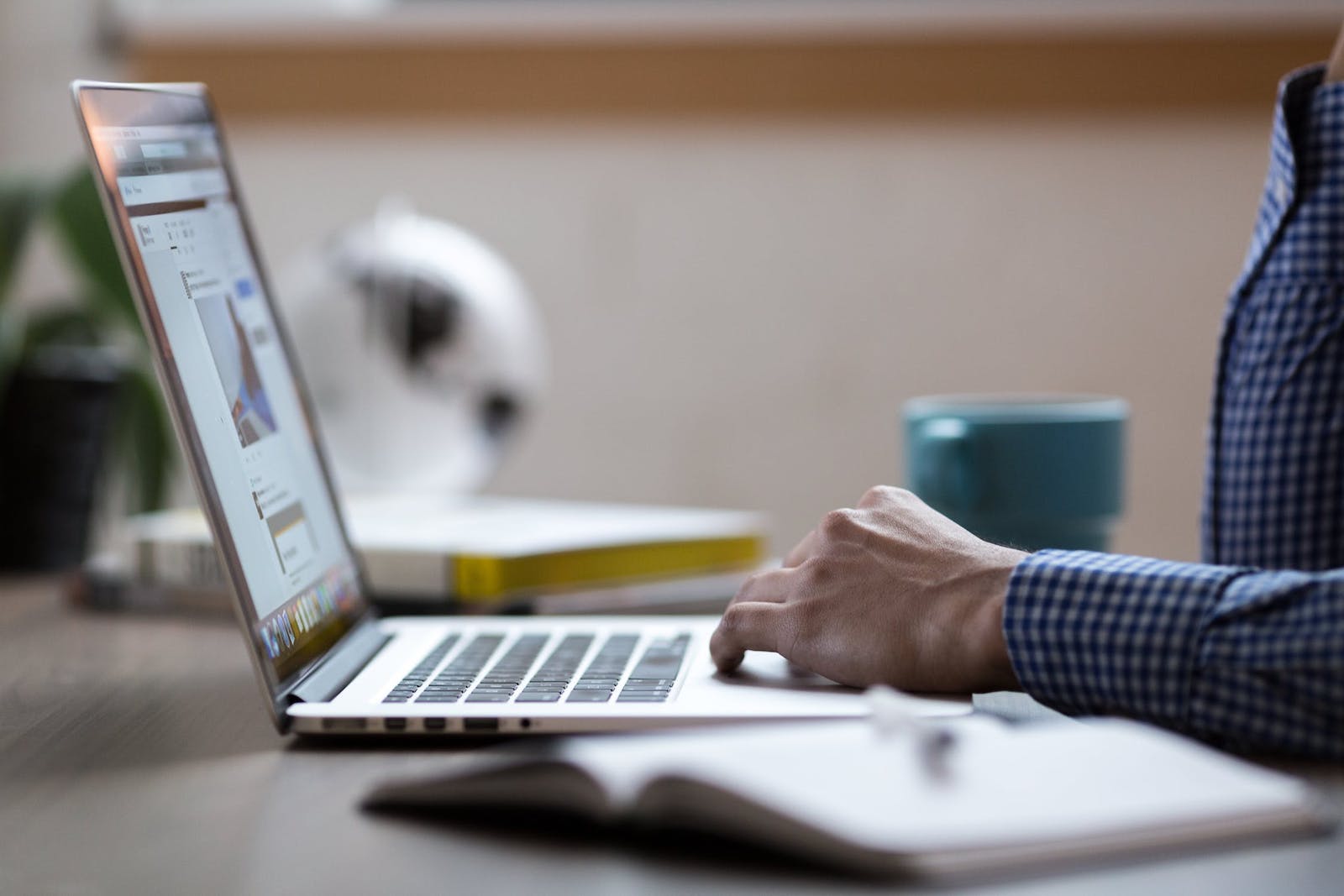 Close-up of a person at a laptop and notebook on the desk