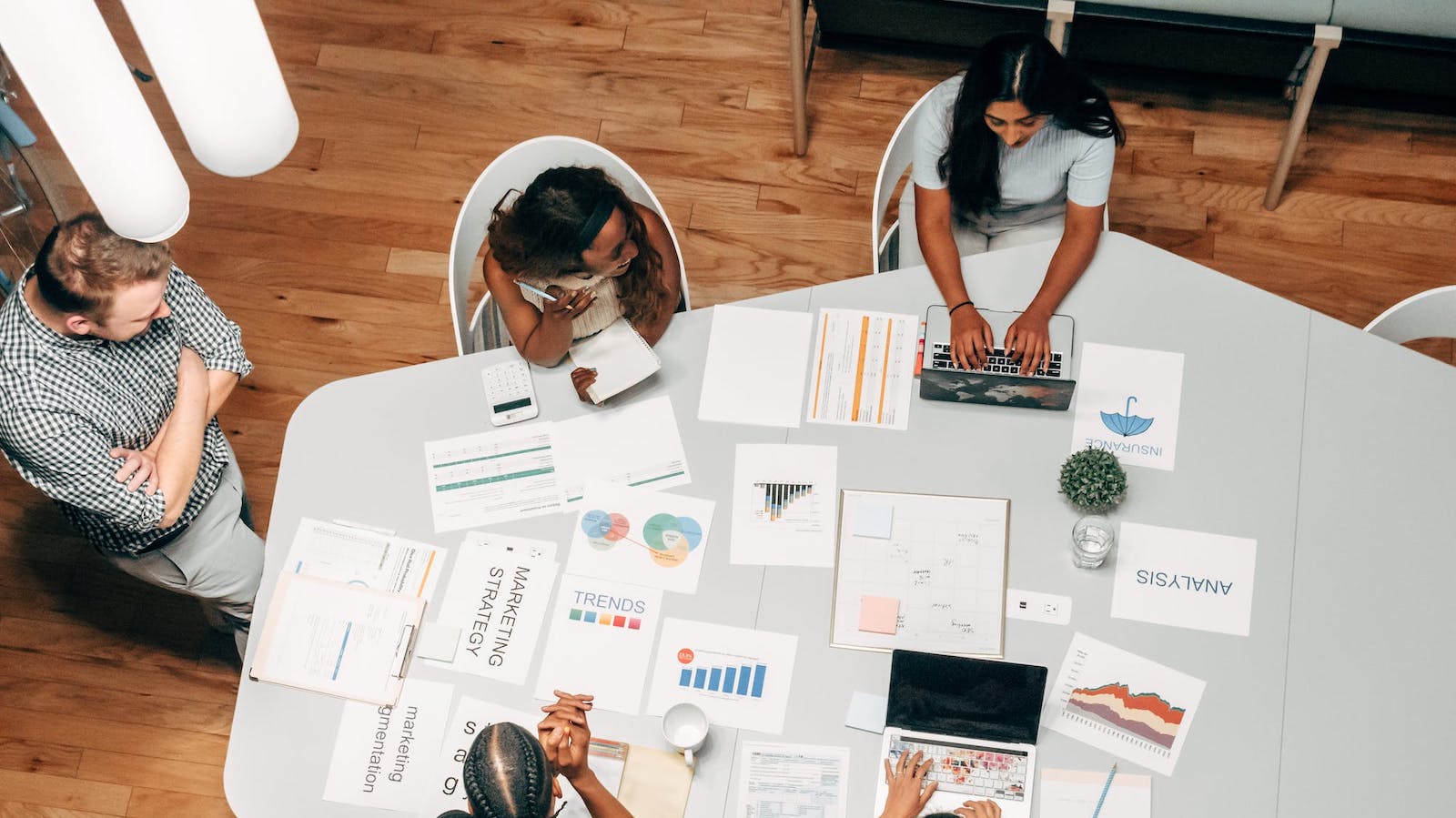 Overhead view of people at a work table with papers with charts in front of them