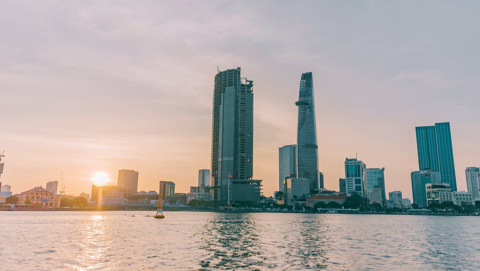 A view of tall buildings from across the water while the sun is setting