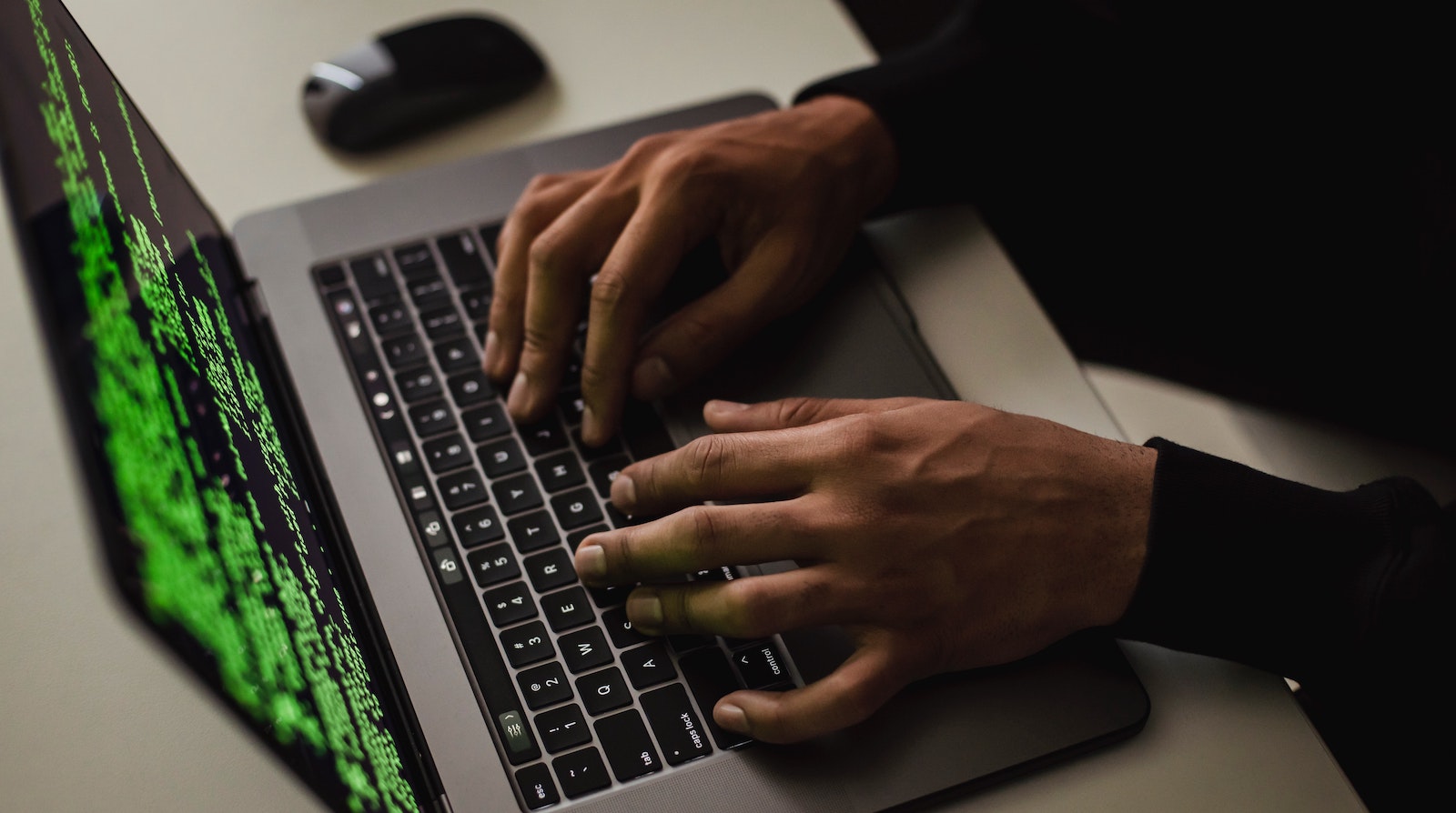 Close-up image of a person typing on a keyboard with bright green words on a black screen