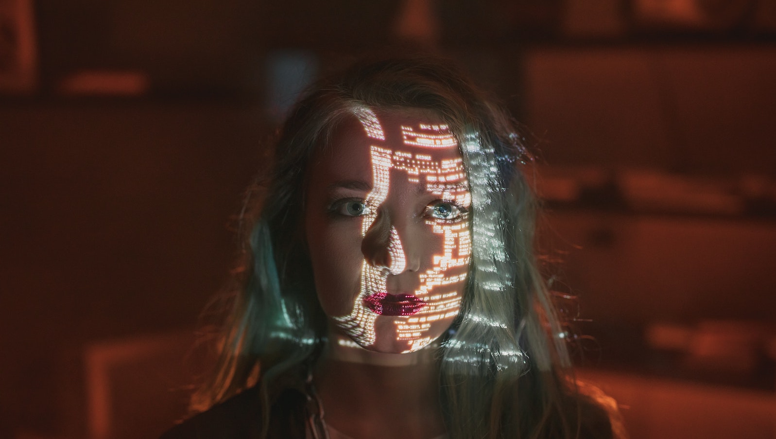 A Woman with Green Hair Looking at the Camera with a dark background and white code text across her face