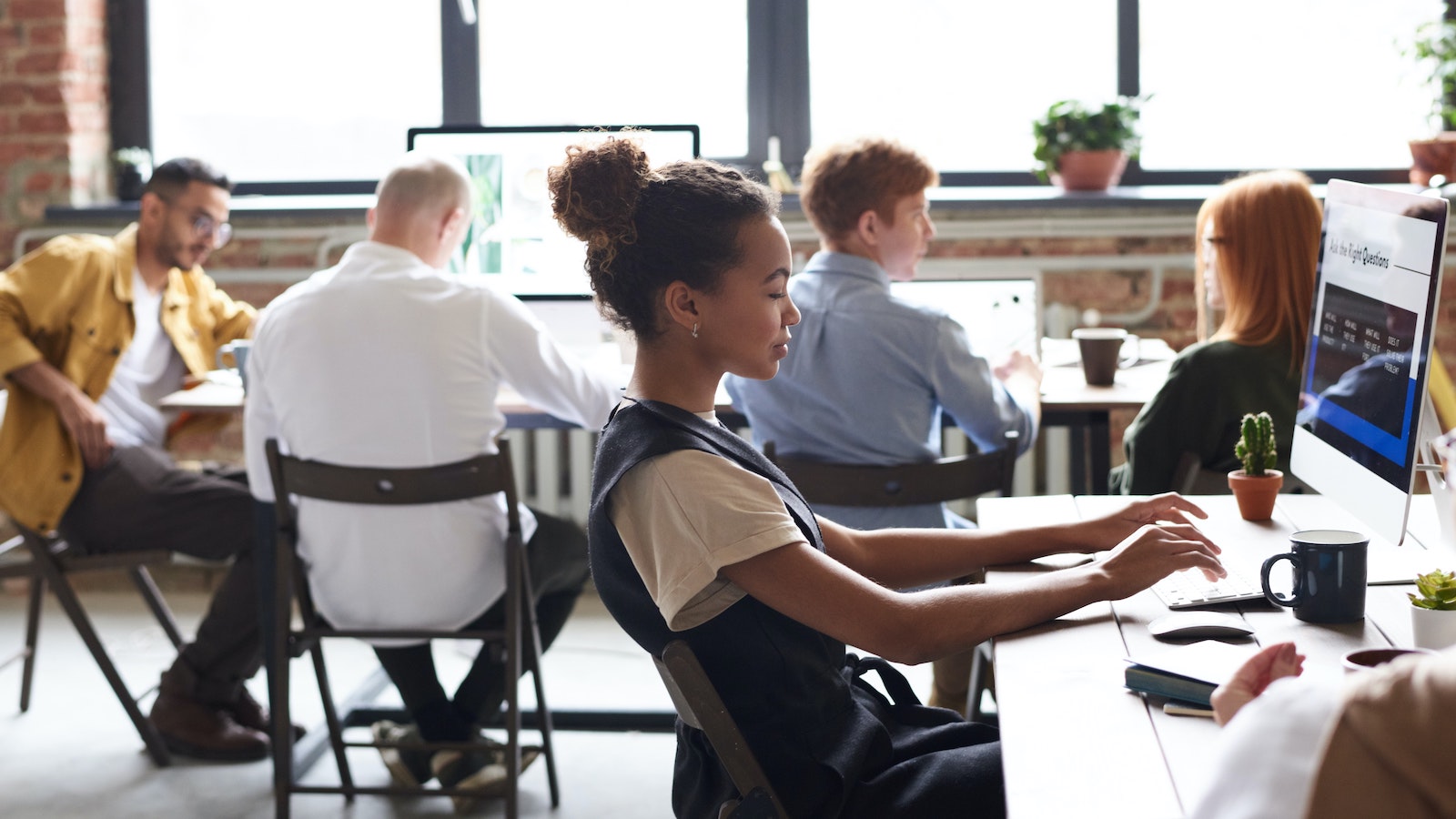 Woman in White and Black Top Using Computer in a room with other people on their laptops