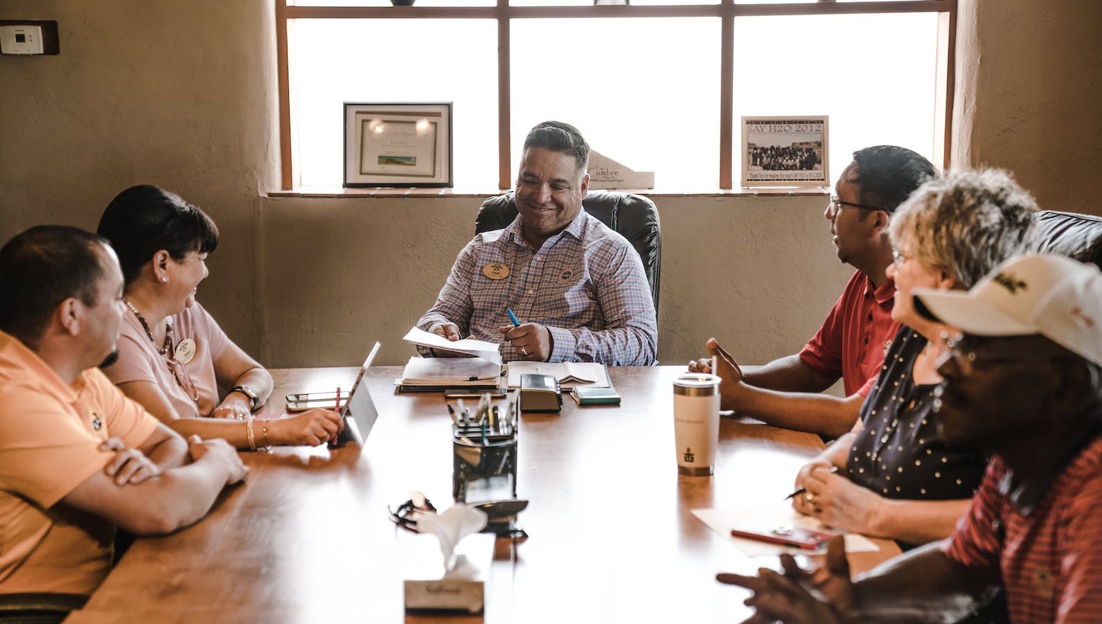 Six people sitting around a table talking and taking notes