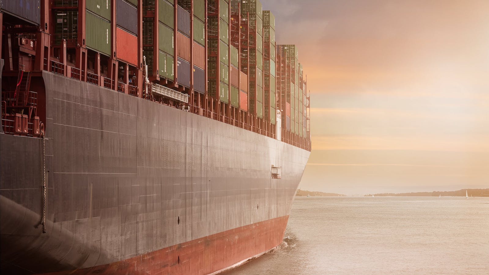 A large cargo boat on a body of water with shipping containers loaded on it