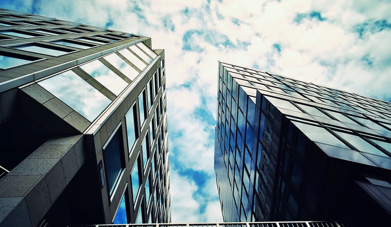 Low angle image of tall glass office buildings against a bright and cloudy sky