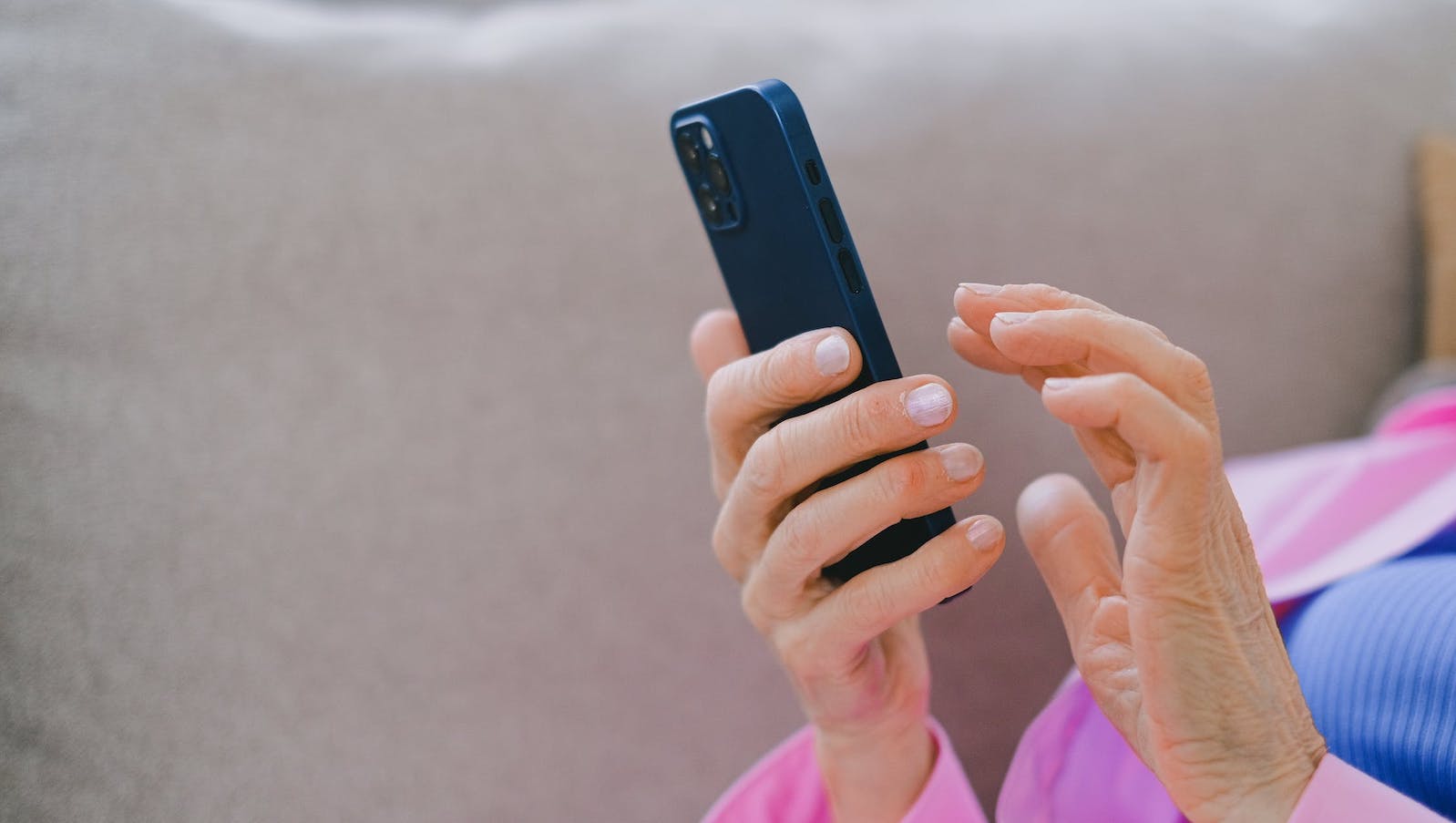 A close-up image of a person's hands holding a black phone