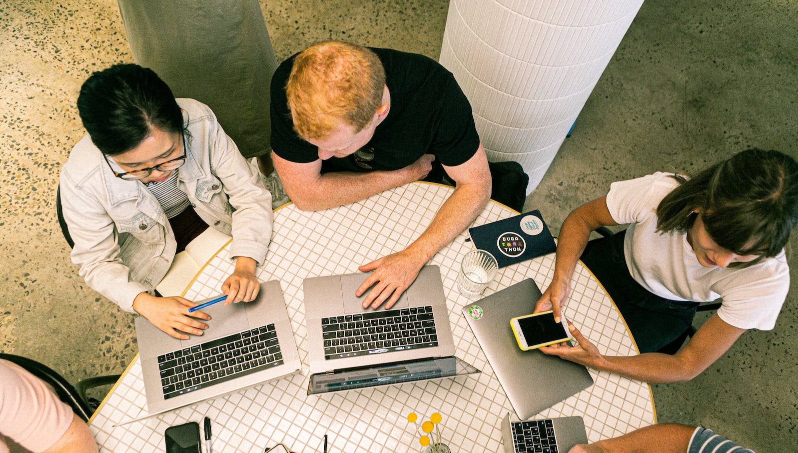 Several people sitting around a table while working on laptops