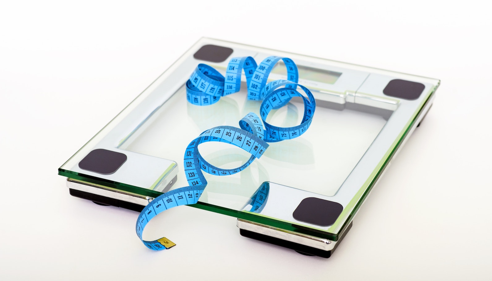 Transparent, clear scale on the floor with a blue tape measure curled on top of it