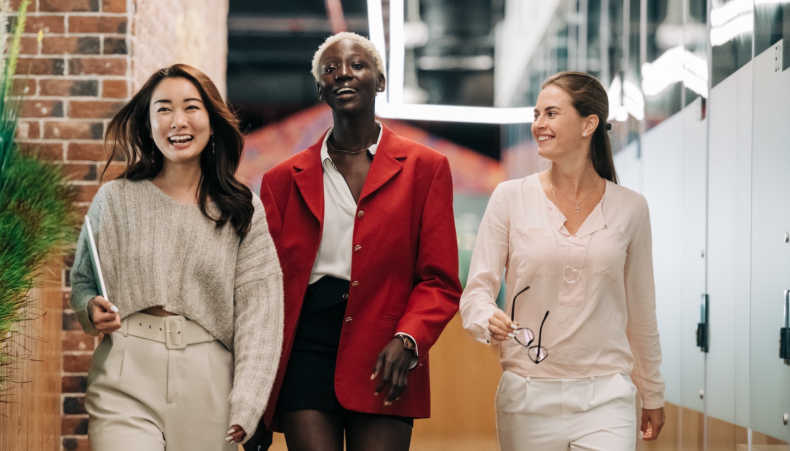 Three women in an office walking side by side while smiling