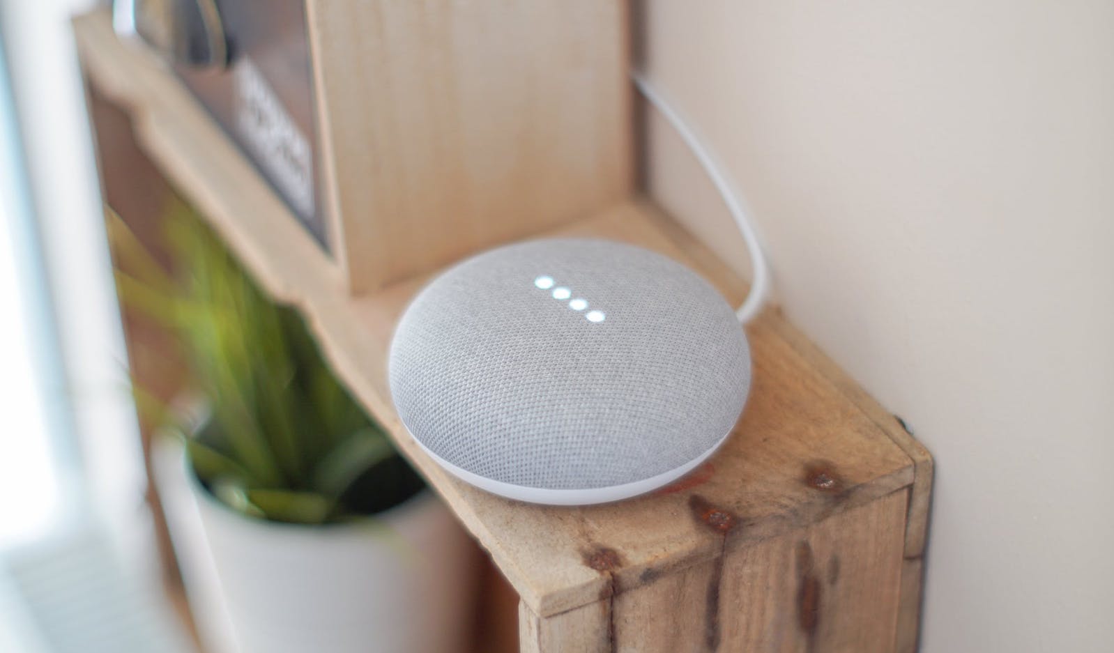 Round grey speaker on top of a wooden shelf with bright lighting