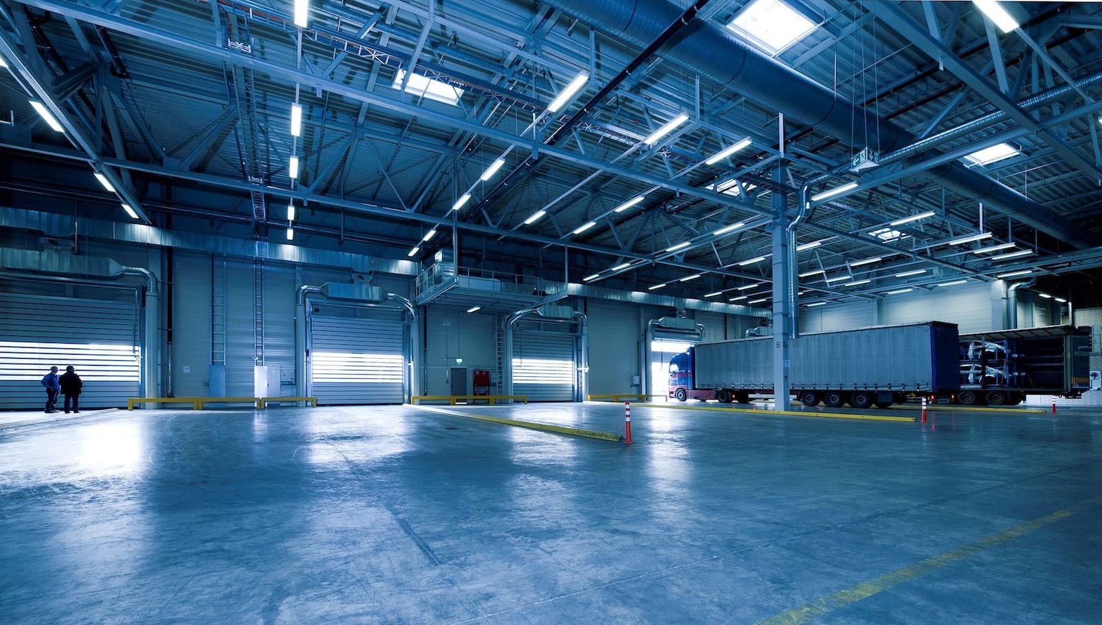 The inside of a mostly empty warehouse with one large truck, all under blue lighting