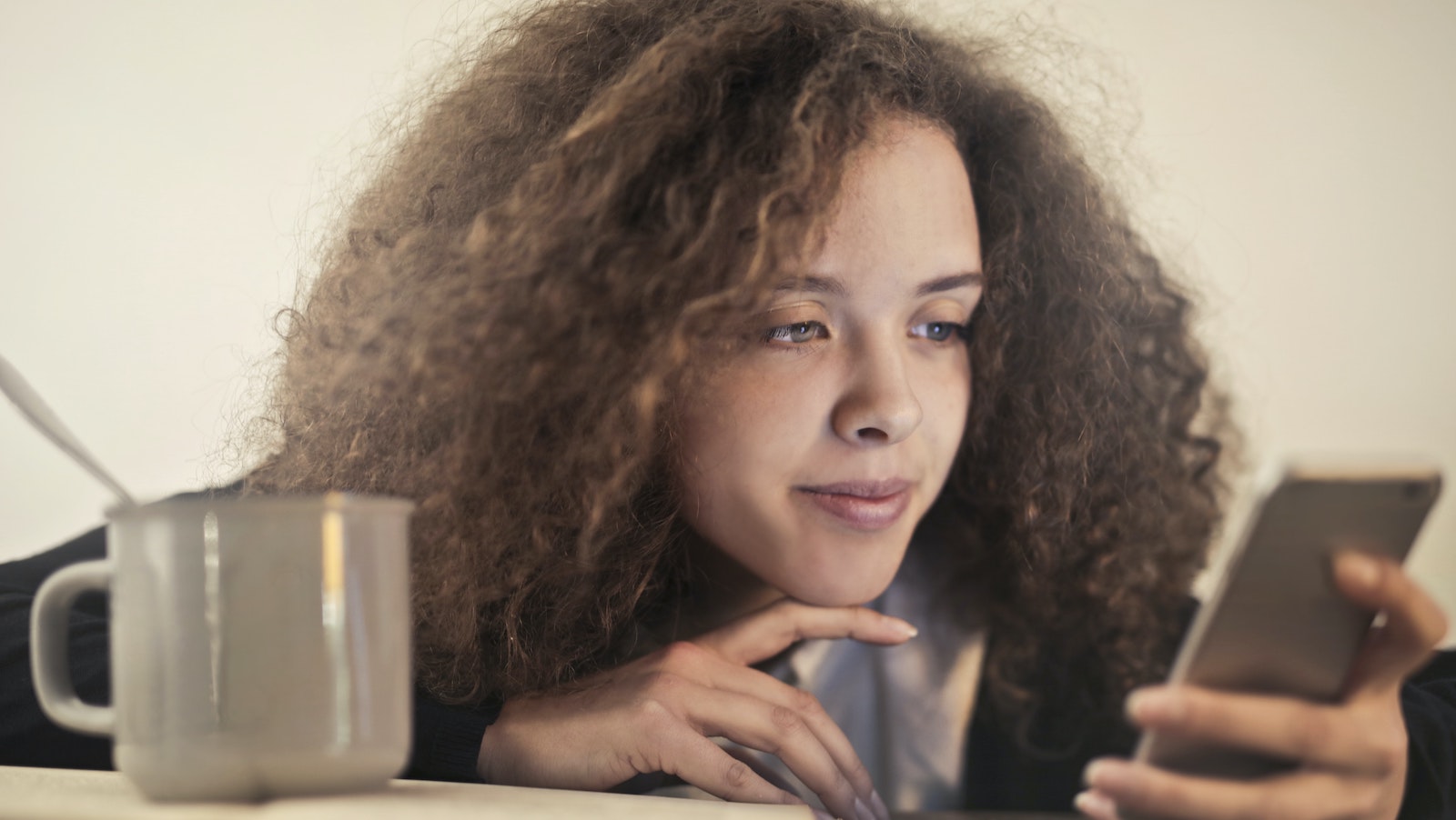 Woman on her phone with a coffee mug next to her