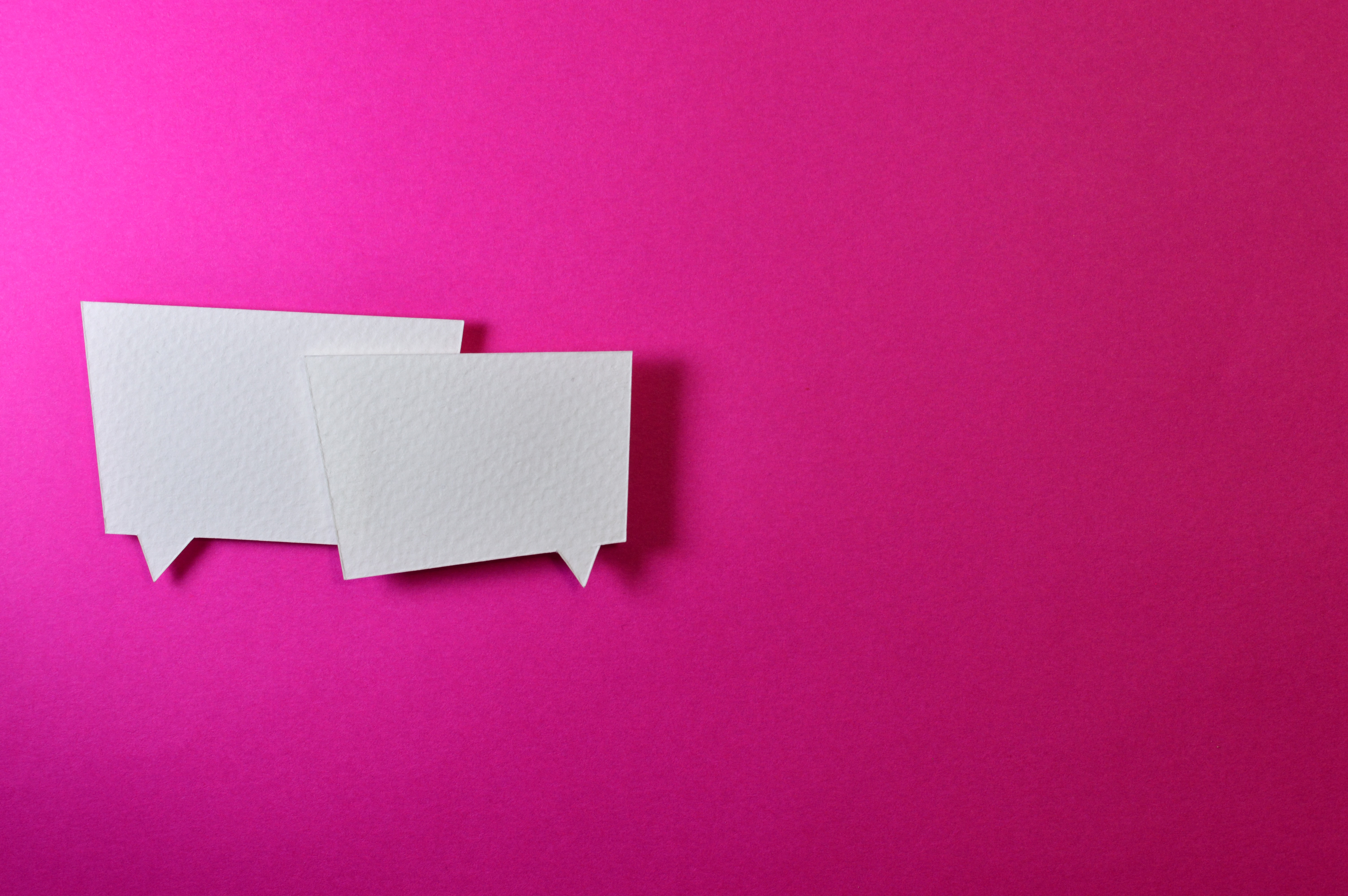 Two overlapping conversation bubbles in white against a hot pink background