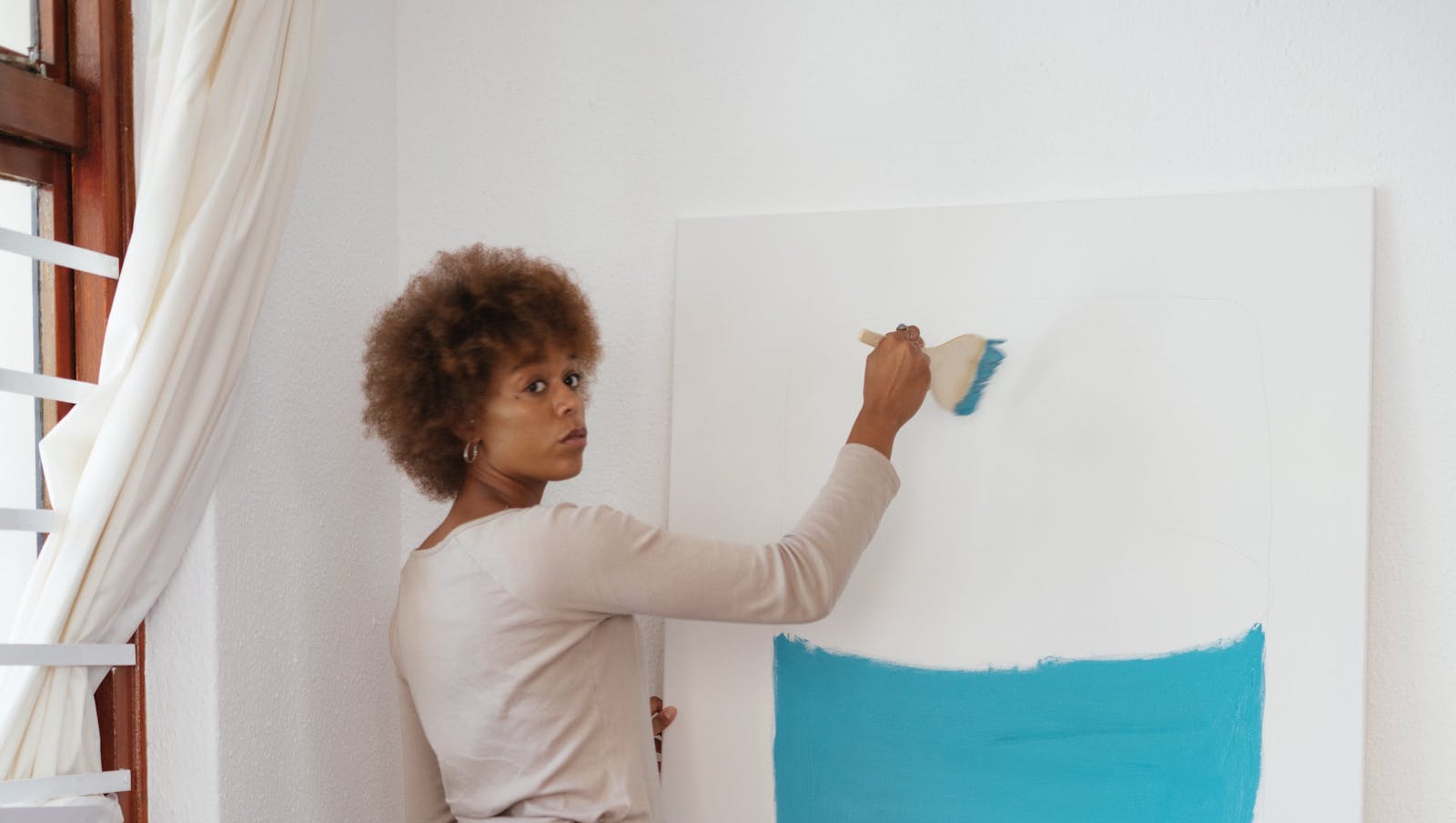 Woman painting a canvas light blue